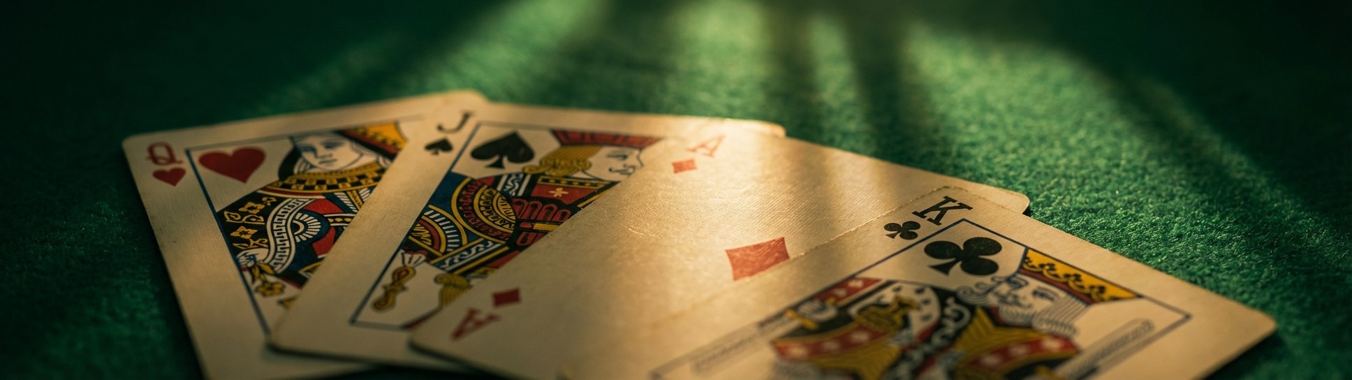 Queens, Jacks and Aces fanned out on green felt - Sheepshead strategy cards